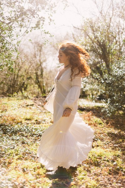 Model bride swings around dances in forest setting trees