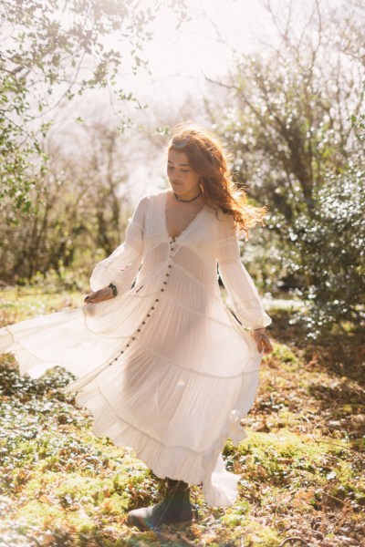 Model bride swings around dances in forest setting trees