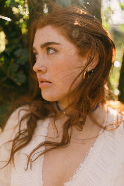 Model bride looks to her side in forest setting hair blowing in wind