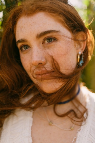 Hair blowing in the wind covering model brides face as she smiles