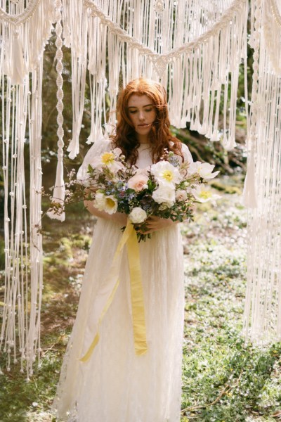 Close up of model brides hand tattoo sunflower yellow white strings behind in forest setting grass