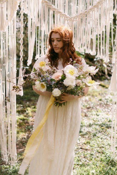 Close up of model brides hand tattoo sunflower yellow white strings behind in forest setting grass