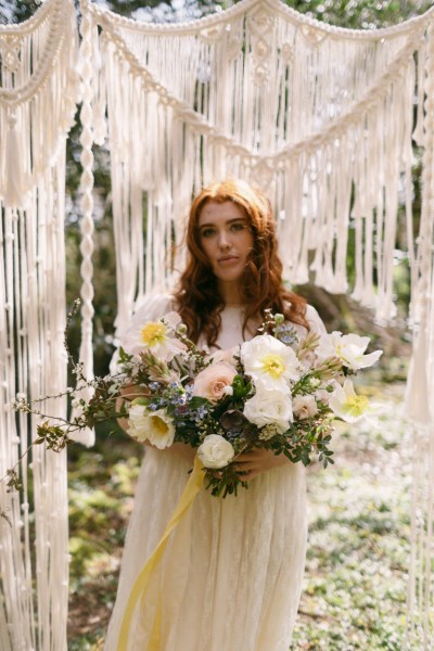 Close up of model brides hand tattoo sunflower yellow white strings behind in forest setting grass