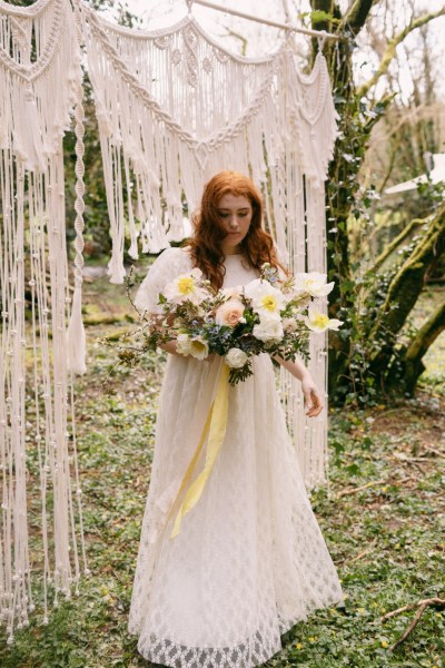 Close up of model brides hand tattoo sunflower yellow white strings behind in forest setting grass