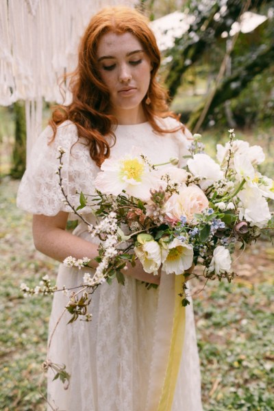 Close up of model brides hand tattoo sunflower yellow white strings behind in forest setting grass