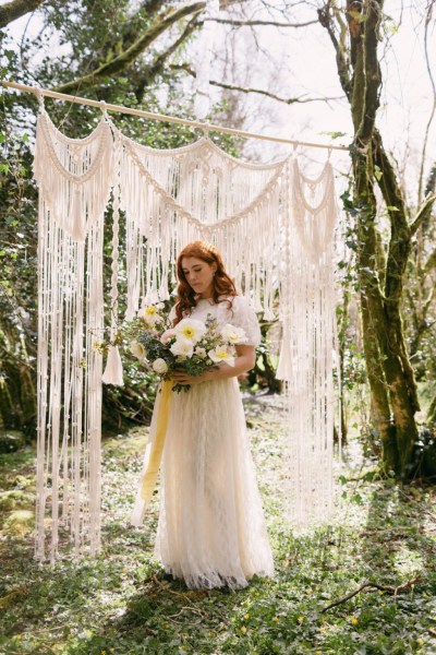 Close up of model brides hand tattoo sunflower yellow white strings behind in forest setting grass