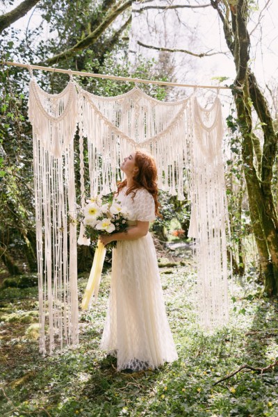 Close up of model brides hand tattoo sunflower yellow white strings behind in forest setting