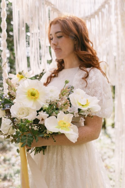 Close up of model brides hand tattoo sunflower yellow white strings behind in forest setting