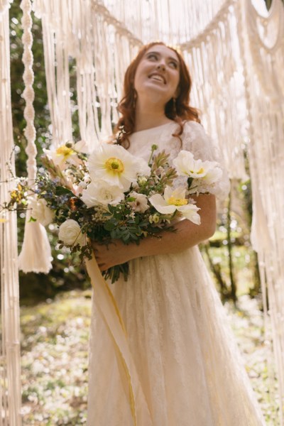 Close up of model brides hand tattoo sunflower yellow white strings behind in forest setting