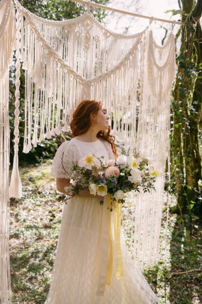 Ruby Rose exterior garden strings behind her she's holding bouquet white flowers sunflowers forest grass