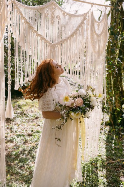 Ruby Rose exterior garden strings behind her she's holding bouquet white flowers sunflowers forest grass