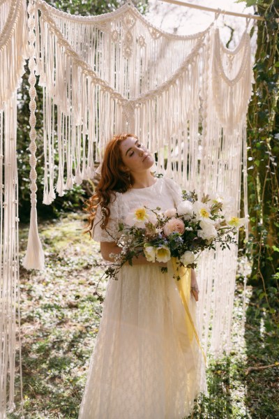 Ruby Rose exterior garden strings behind her she's holding bouquet white flowers sunflowers forest grass