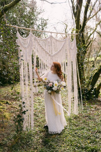 Ruby Rose exterior garden strings behind her she's holding bouquet white flowers sunflowers forest grass