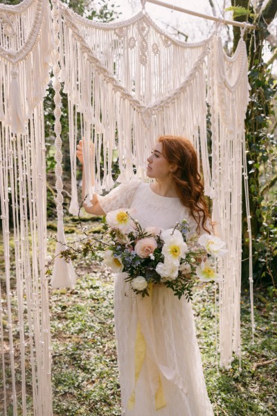 Ruby Rose exterior garden strings behind her she's holding bouquet white flowers sunflowers