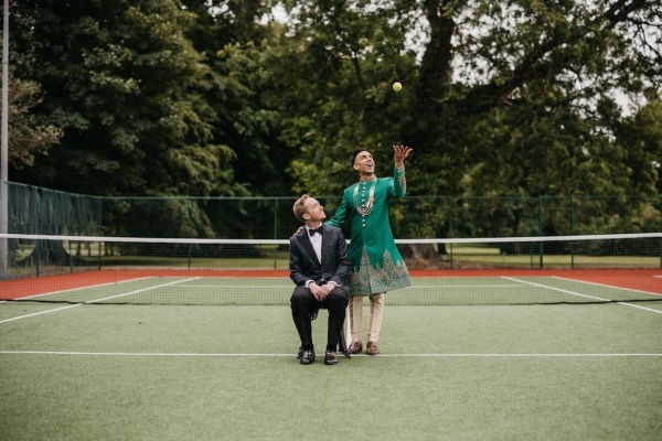 Groom in tennis courtyard throwing ball in air