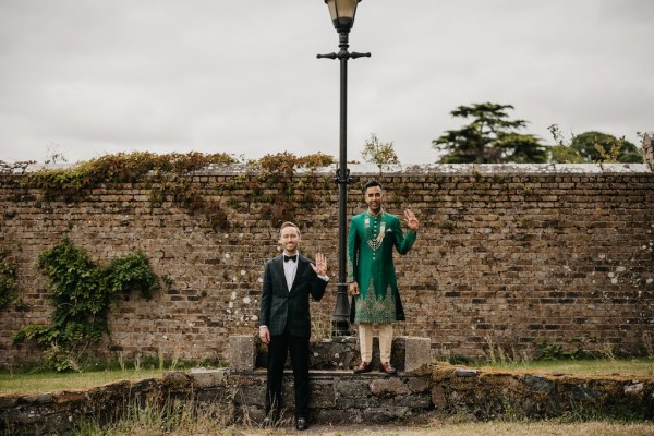 Grooms wave in front of lamppost in garden