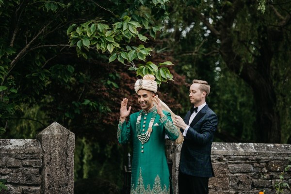 Grooms in garden placing hat on head