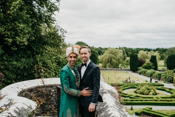 Groom and groom on balcony overlooking garden