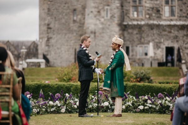 Grooms reading vows in front of guests