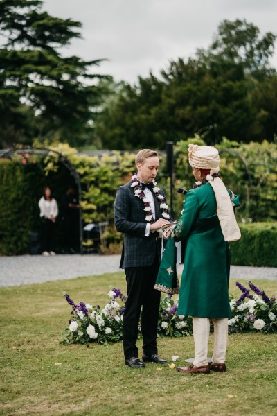 Grooms hold hands at alter