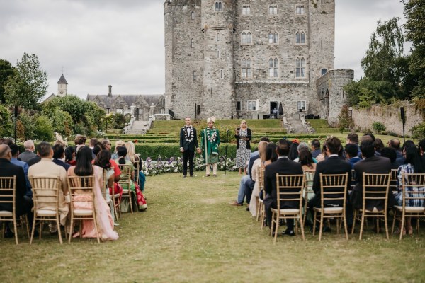 Castle in background grooms at alter with guests seated on grass