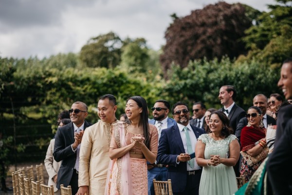 Proud guests smile and clap for couple