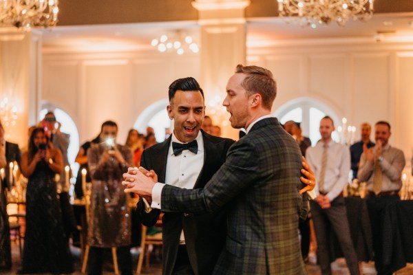 Grooms dancing on dancefloor smiling