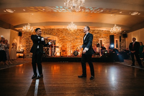 Grooms in suits dancing on dancefloor together