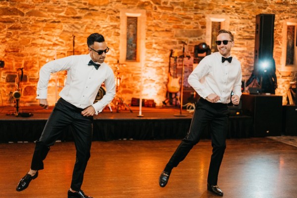 Grooms wearing sunglasses dancing together