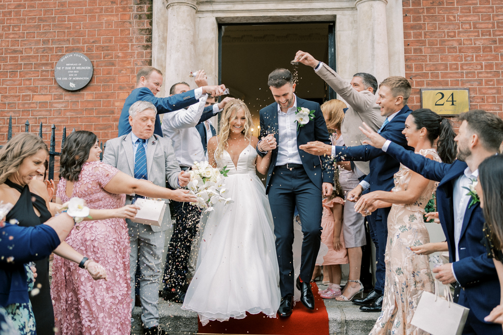 Bride and groom exit ceremony on red carpet guests cheers and throw confetti