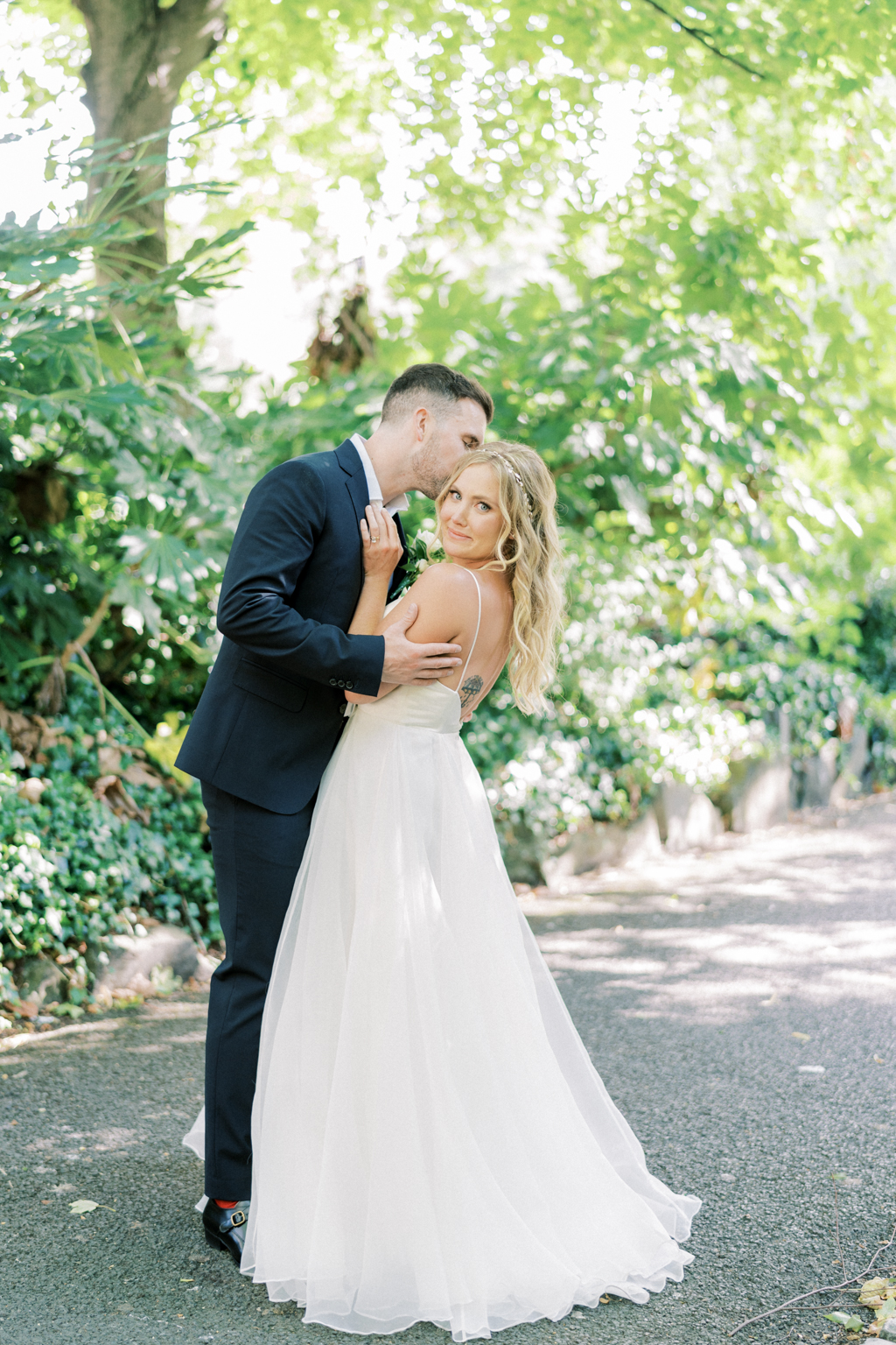 Groom leans in to kiss his bride in garden park forest