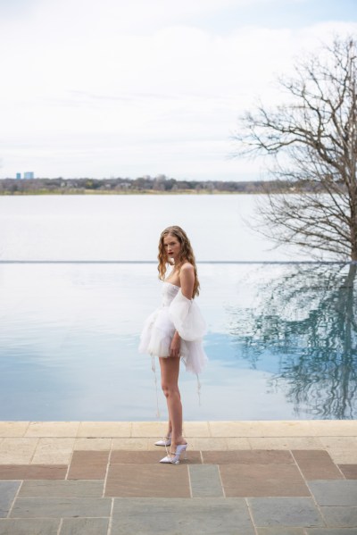 Hermione de Paula's new 2023 collection: 'Moon Phases' model bride standing in front of sea/swimming pool tree reflection in water