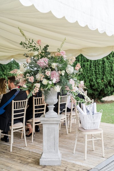 Pink flowers on ornament statue and guests seated