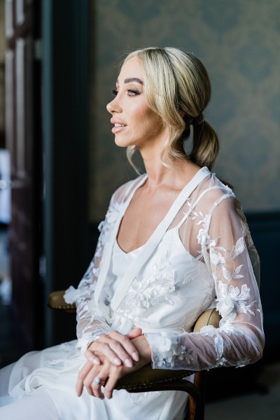 Bride looks out window as she sits down getting ready