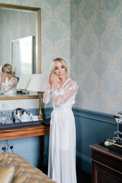 Bride puts on earrings mirror in background