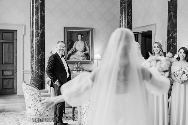 Black and white image of father of the bride veil from behind going in for a hug