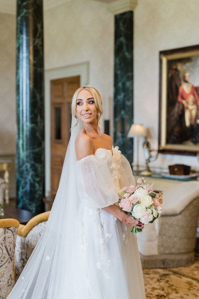 Bride looks over her shoulder and poses with flowers in hand