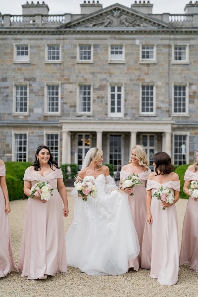 Bride and bridesmaids walk away from wedding venue entrance