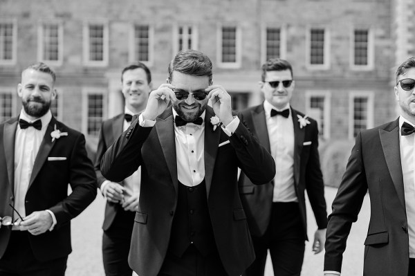 Black and white image of groom and groomsmen wearing sunglasses and bowtie in suits