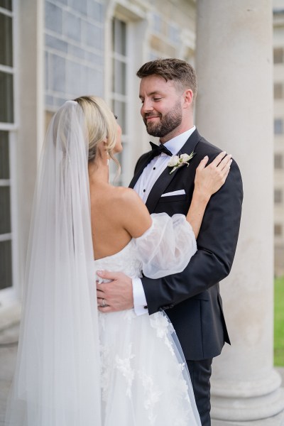 Bride and groom embrace veil from behind smiling