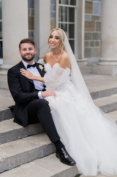 Bride and groom sitting on steps to wedding venue pillars