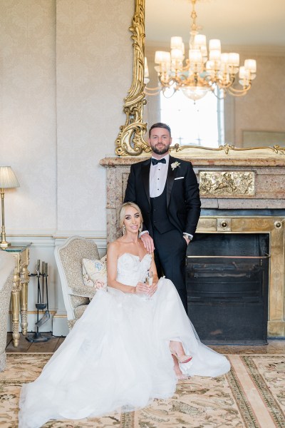 image of bride fixing her earrings sitting down groom behind her