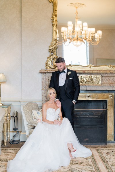 image of bride fixing her earrings sitting down groom behind her