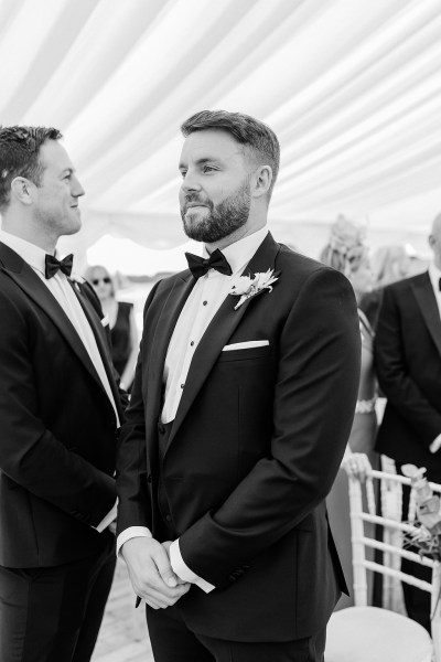 Black and white image of groom awaiting his bride at the alter