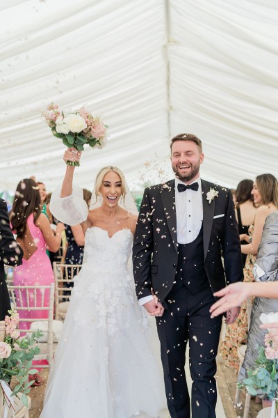 Confetti thrown on couple bride and groom exit ceremonial room guests clap