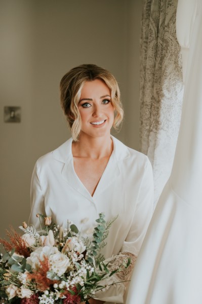 Bride holding bouquet flowers smiling getting ready