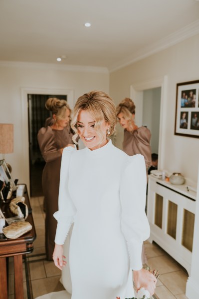 Bride looking down getting ready bridesmaids behind her