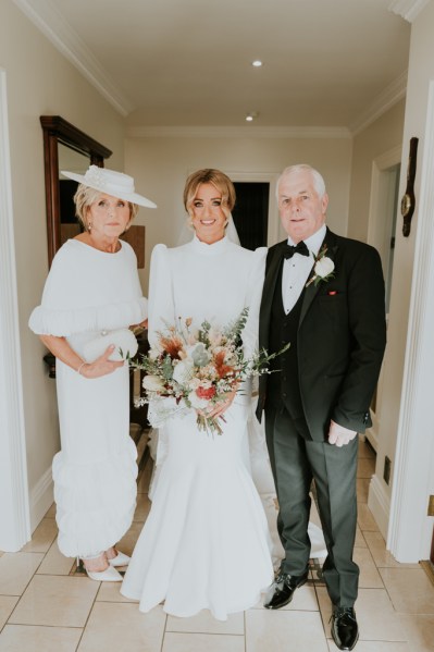 Father mother daughter bride pose for a photo