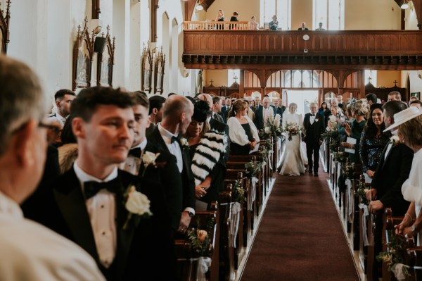 Groom stands awaiting his bride at alter