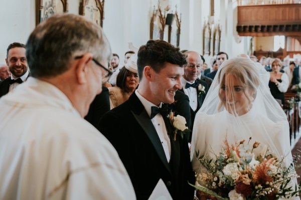 Priest groom and bride smile at the alter